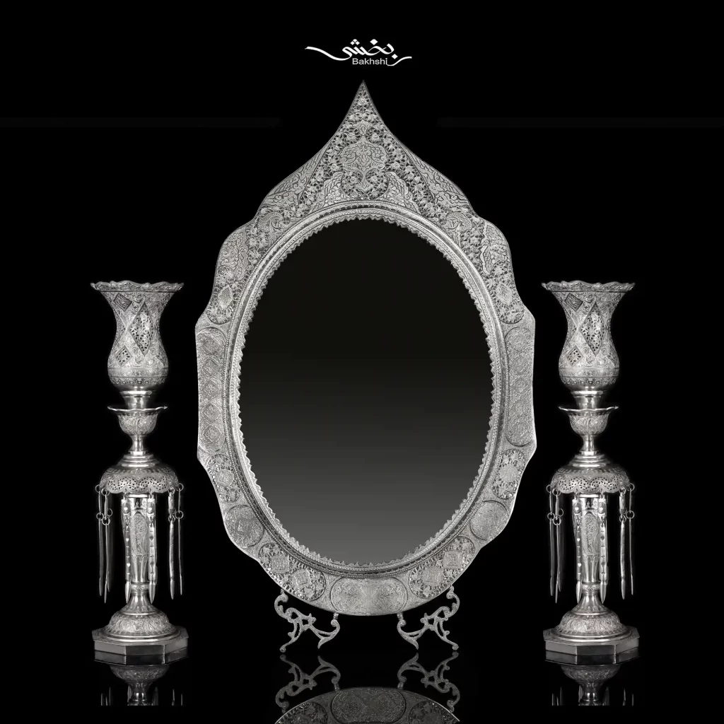 ست آینه تاجدار و شمعدان لاله آویزدار نقره اسلیمی و آینه با ابعاد 82*47 و شمعدان با ارتفاع 50 سانتیمتر و ساخته شده از نقره با عیار 84 موجود در نقره بخشی.